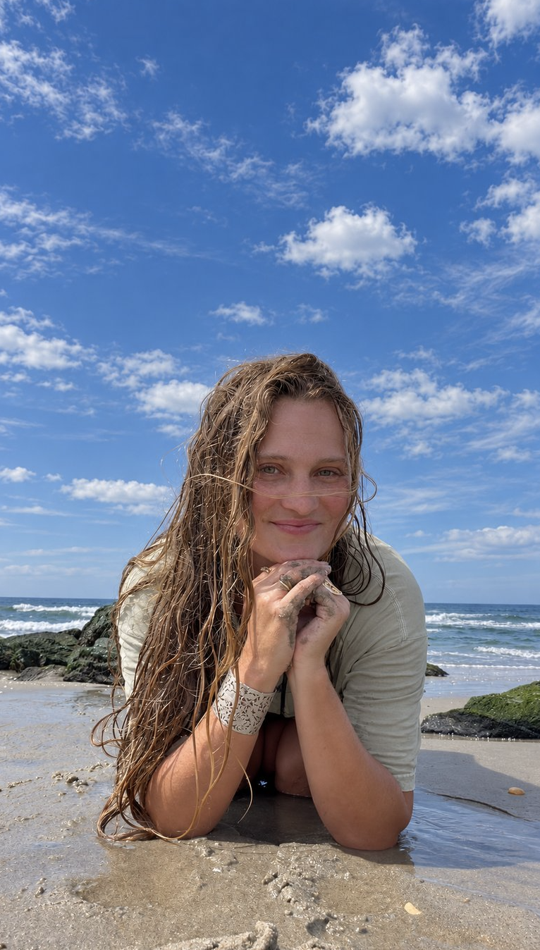 Kir lying on the sand by the ocean, smiling at the camera